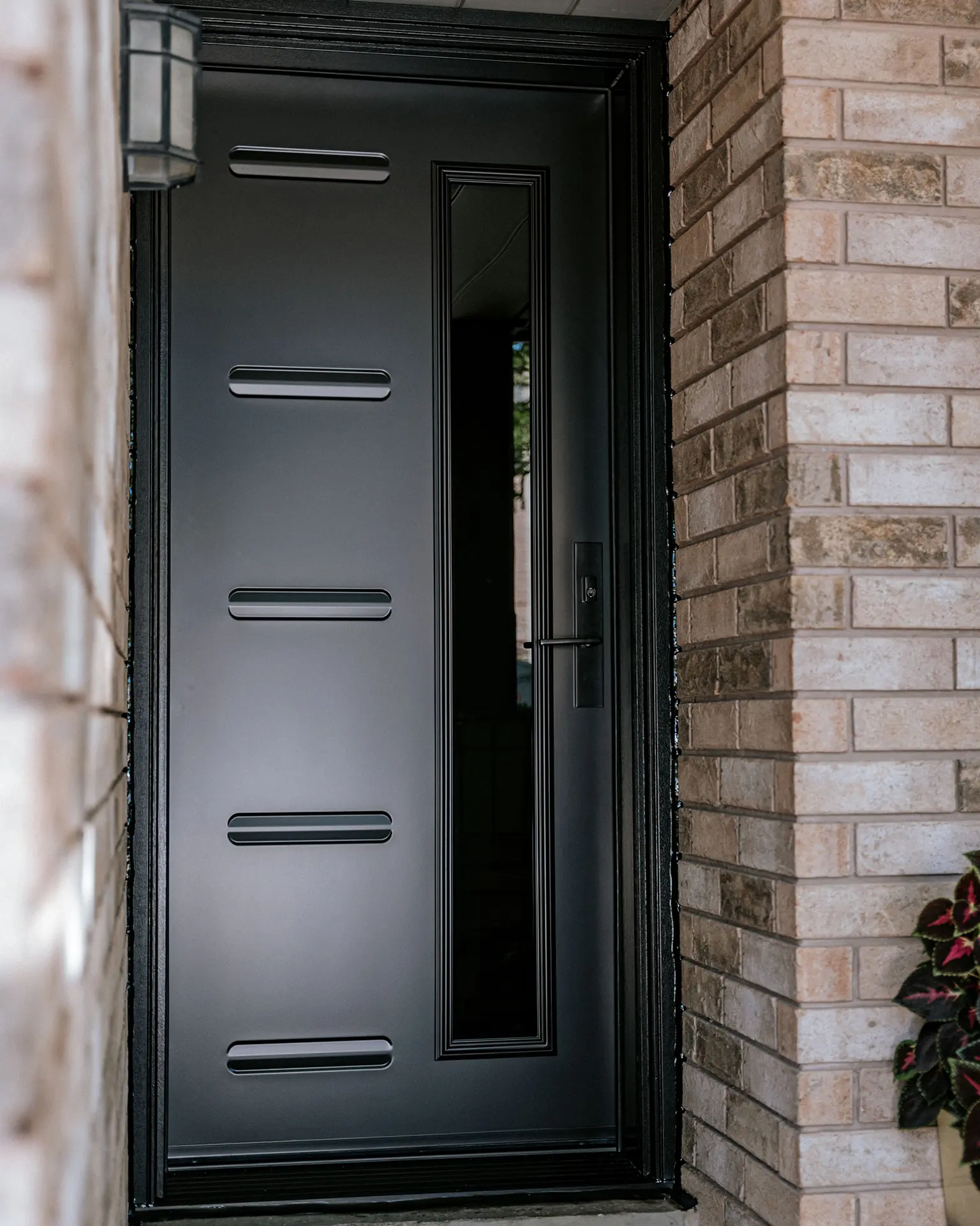 Modern black front door with horizontal decorative elements and a glass insert.