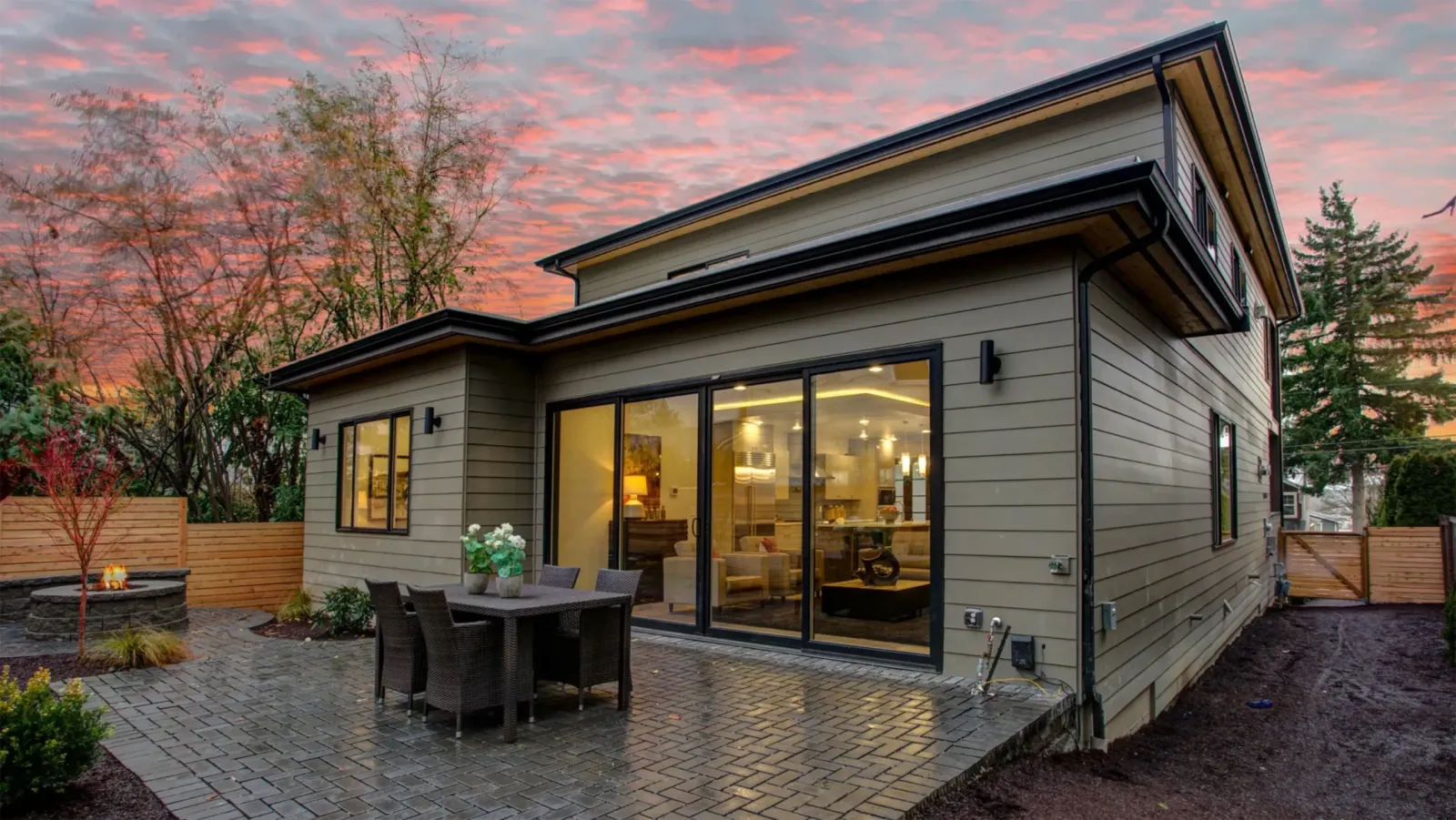 Multi-panel sliding patio door opening onto a paved terrace at dusk