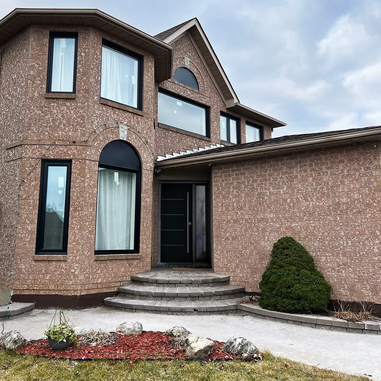 Brick home after full window replacement with black frames
